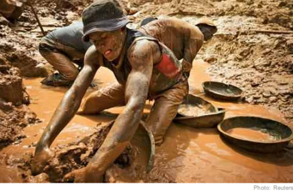 A gold miner scoops mud while digging an open pit at the Chudja mine in the Kilomoto concession near the village of Kobu, 100 km (62 miles) from Bunia in north-eastern Congo 
